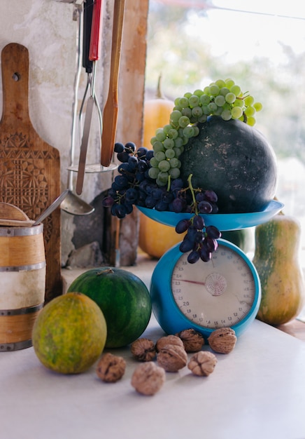 Automne nature morte avec citrouilles, noix, melons, pastèque et raisins à l'échelle et sur un tableau blanc en bois.