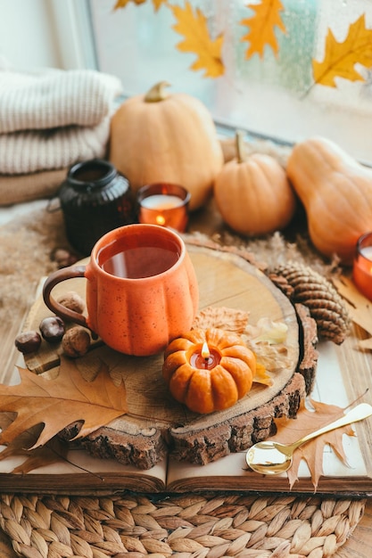 Automne nature morte sur le rebord de la fenêtre une tasse de thé bougies citrouilles feuilles intérieur de la maison de thanksgiving