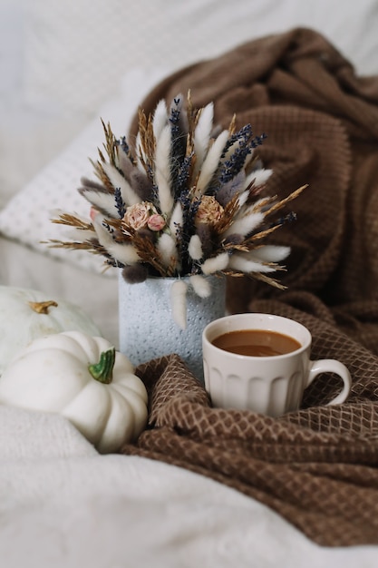 Photo automne nature morte avec une tasse de café avec des fleurs et des citrouilles sur un plaid confortable