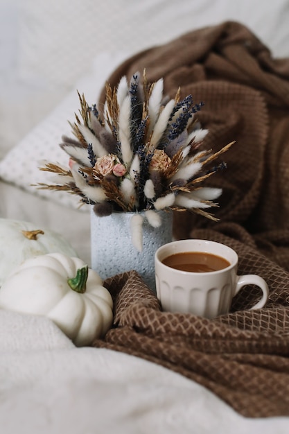 Automne nature morte avec une tasse de café avec des fleurs et des citrouilles sur un plaid confortable