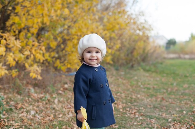 Automne portrait en plein air de belle fille enfant heureux marchant dans le parc ou la forêt en écharpe tricotée chaude