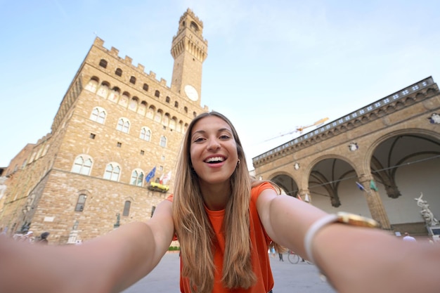 Autoportrait d'une belle voyageuse souriante à la caméra sur la place Piazza della Signoria au coucher du soleil à Florence Italie