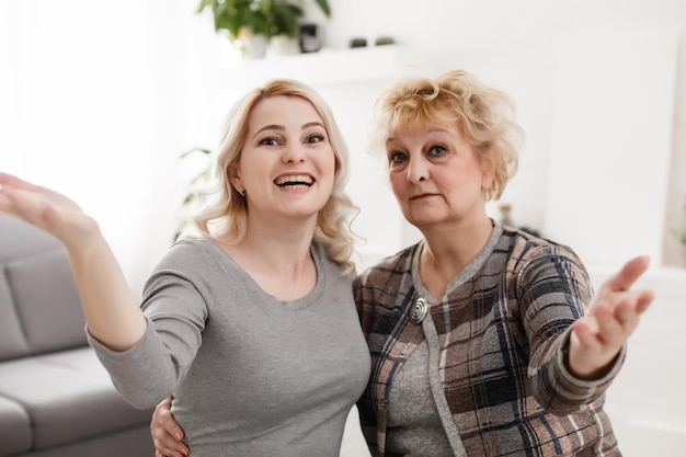 Autoportrait d'une charmante mère et fille funky positives prenant un selfie sur la caméra frontale ayant un appel vidéo assis dans un salon blanc moderne profitant du temps libre