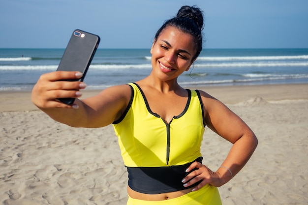 Autoportrait d'une magnifique belle femme indienne prenant une photo de selfie avec un appareil photo de téléphone portable sur une plage tropicale exotique profitant des plages d'été de Goa