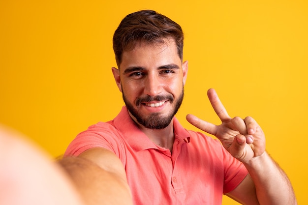 Autoportrait de son beau mec cool gai gai gai et cool montrant le signe v s'amusant isolé sur fond de couleur jaune vif brillant éclatant