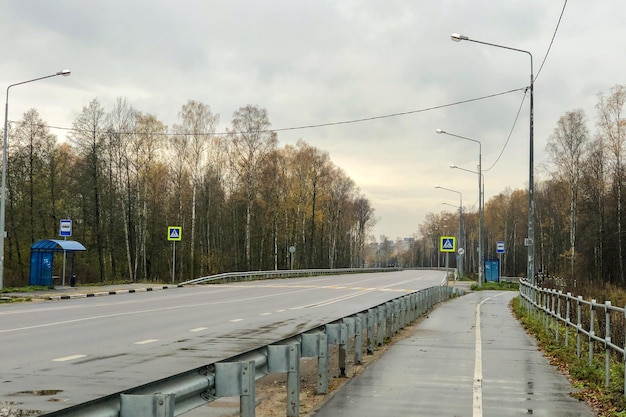 Photo autoroute déserte avec arrêts de bus des deux côtés et panneaux de signalisation pour piétons