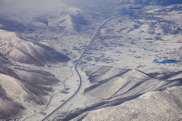 Autoroute de fond de montagnes enneigées entre eux Photo aérienne de la fenêtre de l'avion