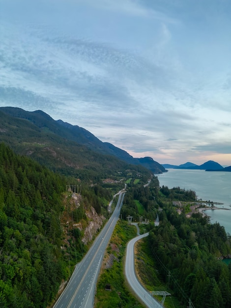 Autoroute panoramique sur la côte océanique avec paysage de montagne. Sea to Sky Hwy, au nord de Vancouver, BC, Canada. Vue aérienne. Coucher de soleil