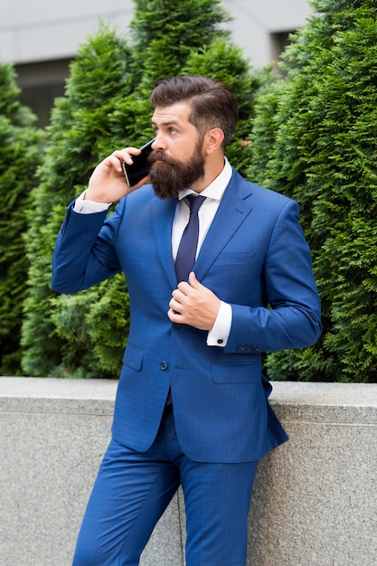 Un autre client. agent d'assurance à succès. votre futur employeur. beau gestionnaire utilise un smartphone. homme en tenue formelle à l'extérieur. veste boutonnée d'agent immobilier. concept de vie moderne. portrait de confiance.