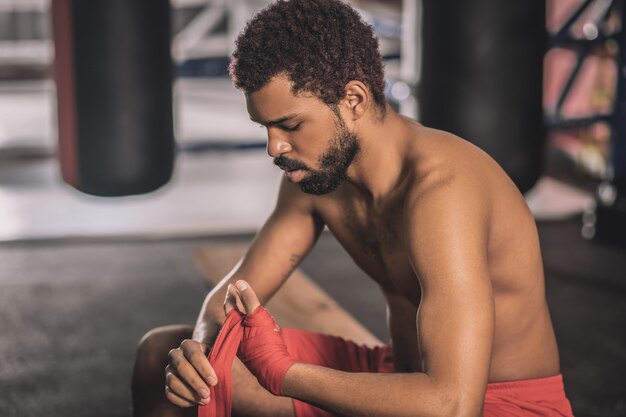 Avant le combat. Athlète à la peau foncée tapant ses mains avec un bandage rouge