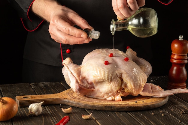 Avant la cuisson, le chef ajoute de l'huile végétale au poulet cru