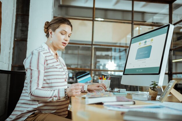 Avant de l'ordinateur. Belle femme enceinte s'asseyant devant l'ordinateur et travaillant dur