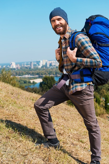 En avant et seulement en avant ! Beau jeune homme portant un sac à dos et regardant la caméra avec le sourire