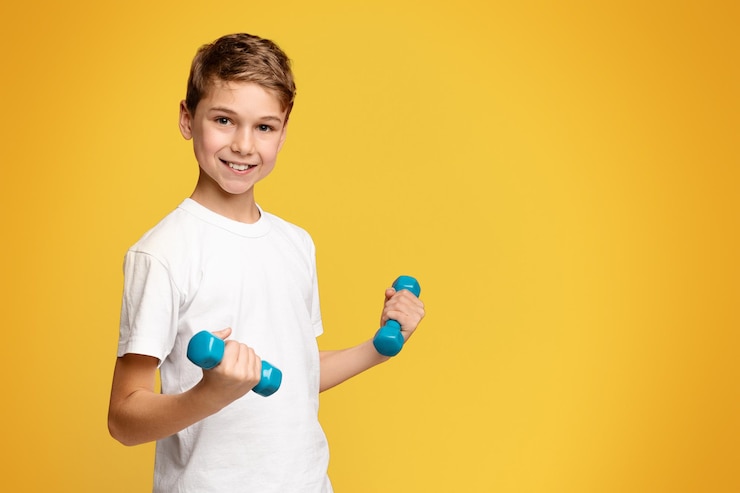 Photo avantages de l'entraînement physique garçon joyeux faisant de l'exercice avec des haltères fond panoramique orange avec