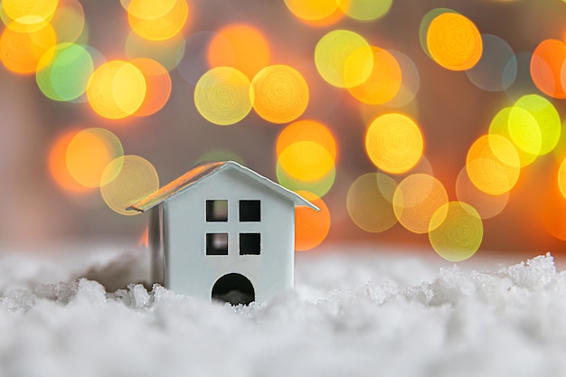 Avent abstrait fond de noël maison modèle de jouet sur la neige avec des lumières de guirlande défocalisées backgroun