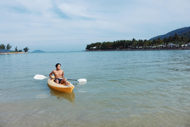 Photo une aventure amusante sur la plage un homme asiatique apprécie le kayak dans un paradis tropical