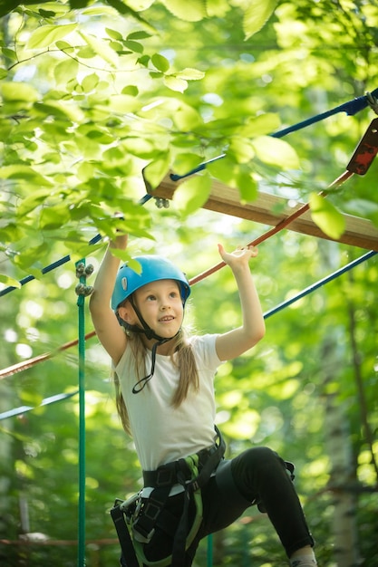 Aventure de corde dans la forêt petite fille souriante debout sur le pont de corde en levant