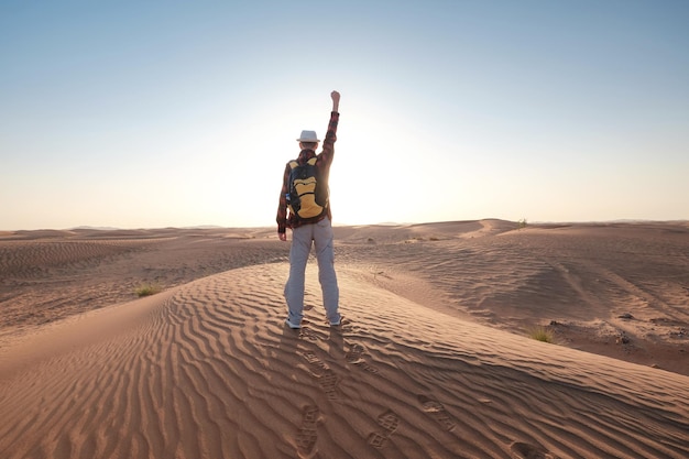 Aventure dans le désert Jeune homme avec sac à dos marchant sur des dunes de sable Dubaï Émirats Arabes Unis