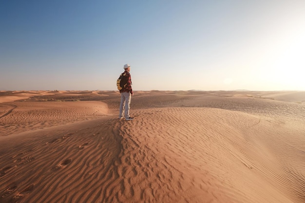 Aventure dans le désert Jeune homme avec sac à dos marchant sur des dunes de sable Dubaï Émirats Arabes Unis