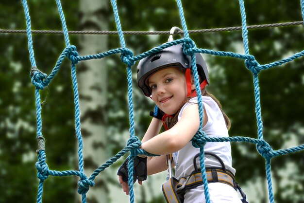 Aventure escalade personnes du parc à fil élevé sur le parcours du casque de montagne et de l'équipement de sécurité