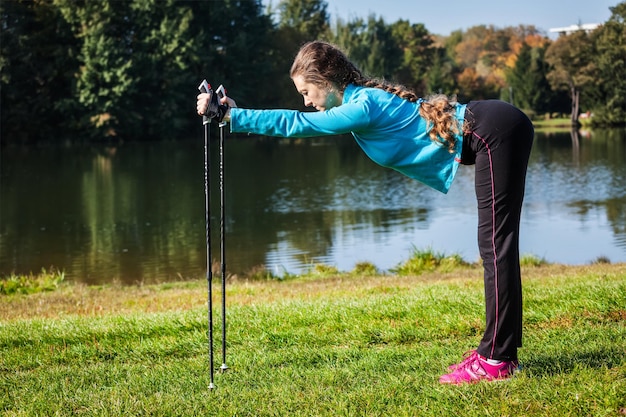 Aventure de marche nordique et concept d'exercice femme faisant de l'exercice avec des bâtons de marche nordique dans le parc
