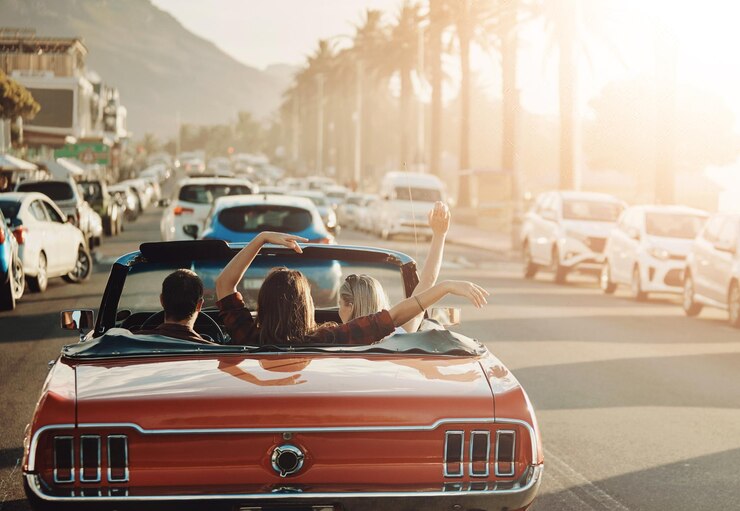 Photo aventure ville et amis en voiture pour un road trip au coucher du soleil pour des vacances vacances ou voyage liberté de voyage et le dos des gens dans un véhicule décapotable pour conduire à une destination de week-end en californie