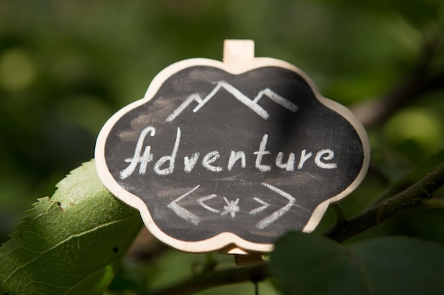 L'aventure vous attend concept petit panneau avec l'inscription d'aventure à l'extérieur vert arrière-plan flou