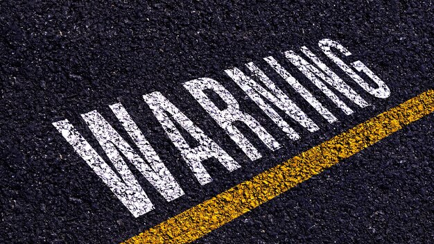 Avertissement écrit et ligne jaune sur la route au milieu de la route goudronnée Mot d'avertissement sur la rue