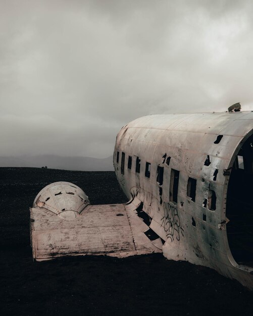 Photo un avion abandonné sur la plage contre un ciel nuageux