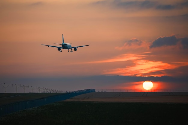 Avion atterrissant sur la piste de l'aéroport au beau coucher de soleil thèmes voyages et aviation