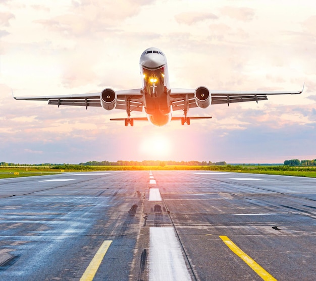 Avion atterrissant sur la piste de l'aéroport à l'aube du coucher du soleil