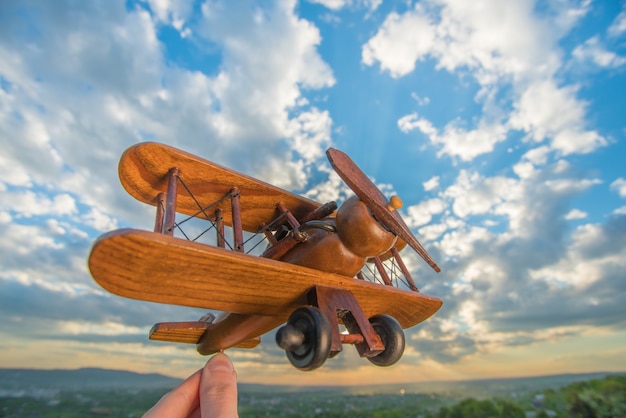 L'avion en bois de prise de main sur le fond d'un ciel bleu