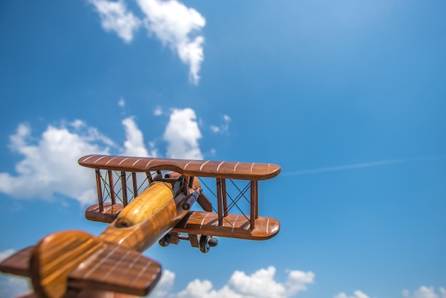 L'avion en bois vole sur le fond de nuage