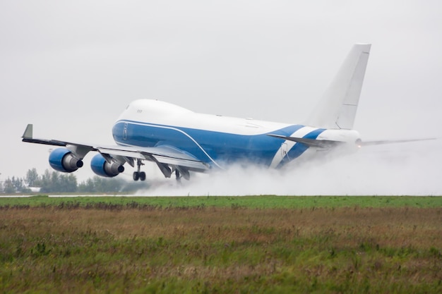 L'avion cargo à fuselage large décolle sous une forte pluie laissant derrière lui un nuage d'éclaboussures