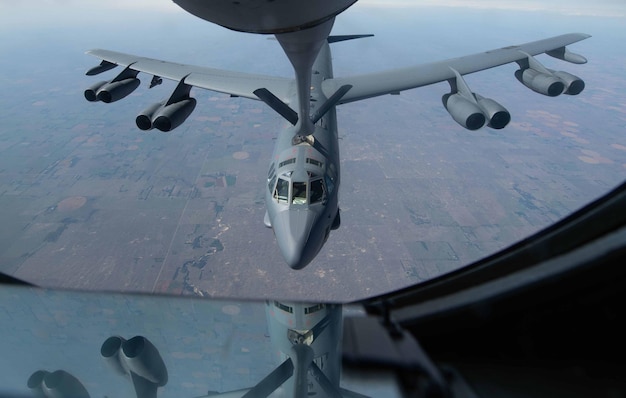 Un avion de chasse survole un champ et le ciel est visible.