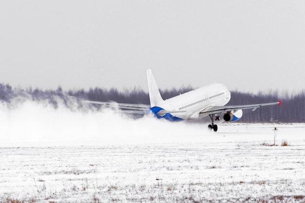 Avion décoller de l'aéroport de piste couverte de neige par mauvais temps lors d'une tempête de neige