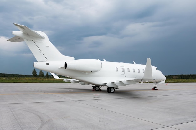 Avion exécutif blanc moderne sur l'aire de trafic de l'aéroport par temps nuageux