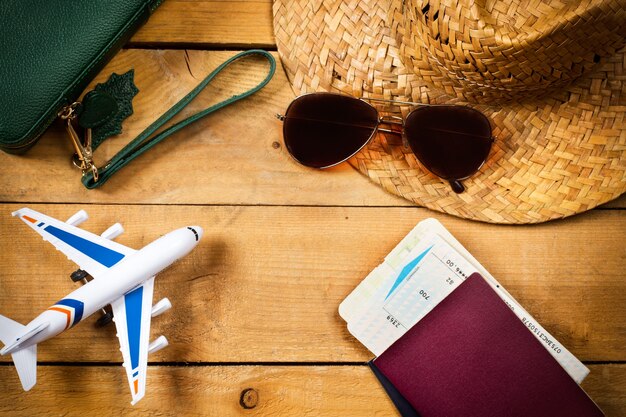 Un avion jouet, un passeport et une carte d'embarquement sur fond rose