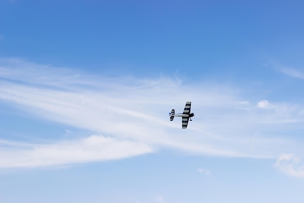 Avion jouet radiocommandé contre un ciel bleu avec des nuages blancs. Avion modèle RC volant dans le ciel bleu. Passe-temps d'avion.