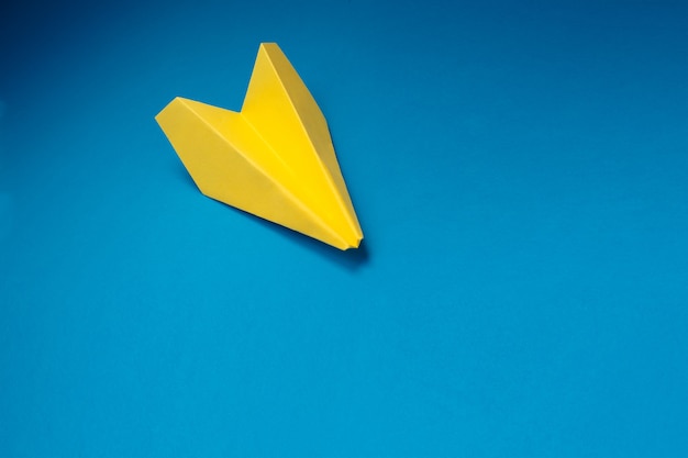 Avion origami jaune sur fond bleu