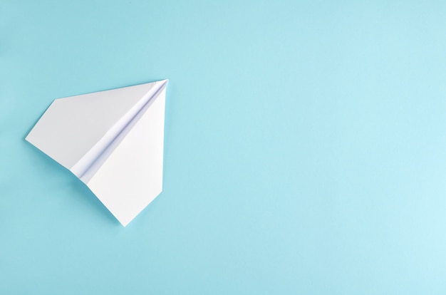 Photo avion en papier blanc sur la surface bleue.
