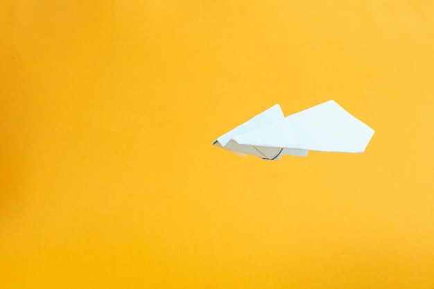 Photo l'avion de papier blanc vole sur les vols et les voyages de concept de fond jaune.