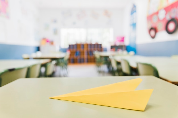 Photo avion en papier jaune sur le bureau dans la salle de classe