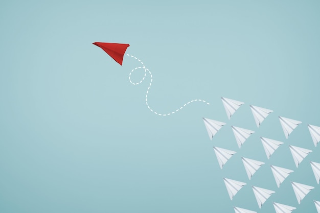 Un avion en papier rouge unique dirige le groupe d'avions en papier blanc sur fond bleu clair. Concept de leadership idéal créatif d'entreprise ou de conception.