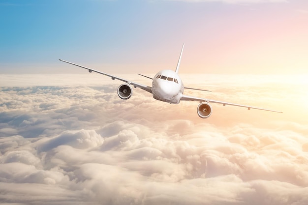 Avion de passagers volant au-dessus du ciel d'horizon de nuages avec des couleurs vives du coucher du soleil.