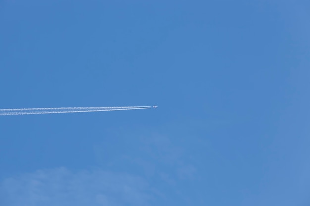 Avion de passagers volant dans le ciel bleu, le transport rapide laisse derrière lui une traînée de traînée blanche