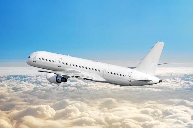 L'avion de passagers vole sur une hauteur au-dessus des nuages couverts et du ciel bleu.