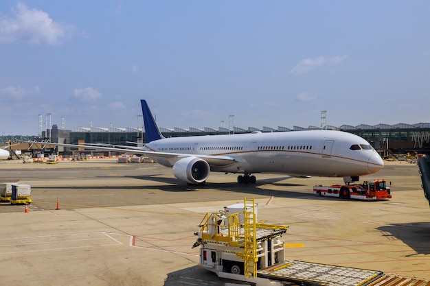 Avion de passagers à la vue de l'aéroport avec des avions et des véhicules de service près du terminal de l'aéroport international d'embarquement