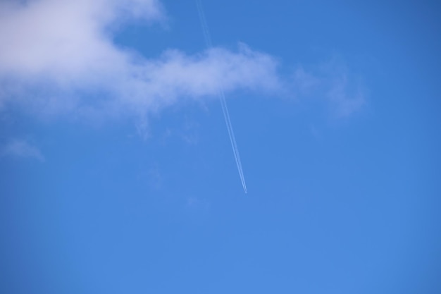 Avion à réaction de passagers lointain volant à haute altitude sur un ciel bleu avec des nuages blancs laissant une trace de fumée derrière le concept de voyage aérien