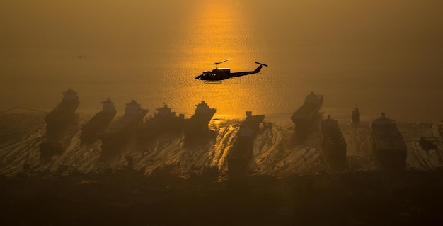 Un avion en silhouette survolant la plage contre le ciel au coucher du soleil